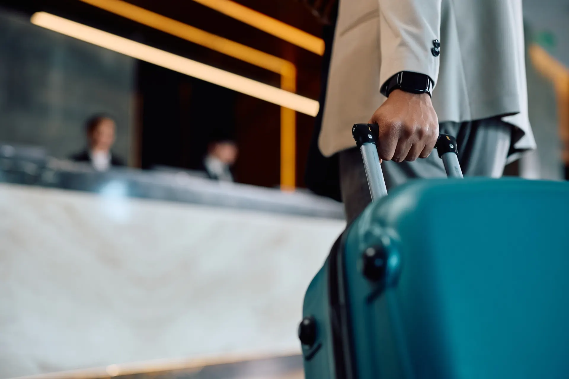 Gość hotelowy z walizką przy recepcji w czasie zameldowania
